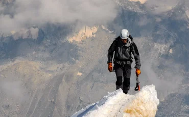 Illustration of a determined hiker ascending a mountain made of books labeled in different languages, symbolizing gradual language learning progress.